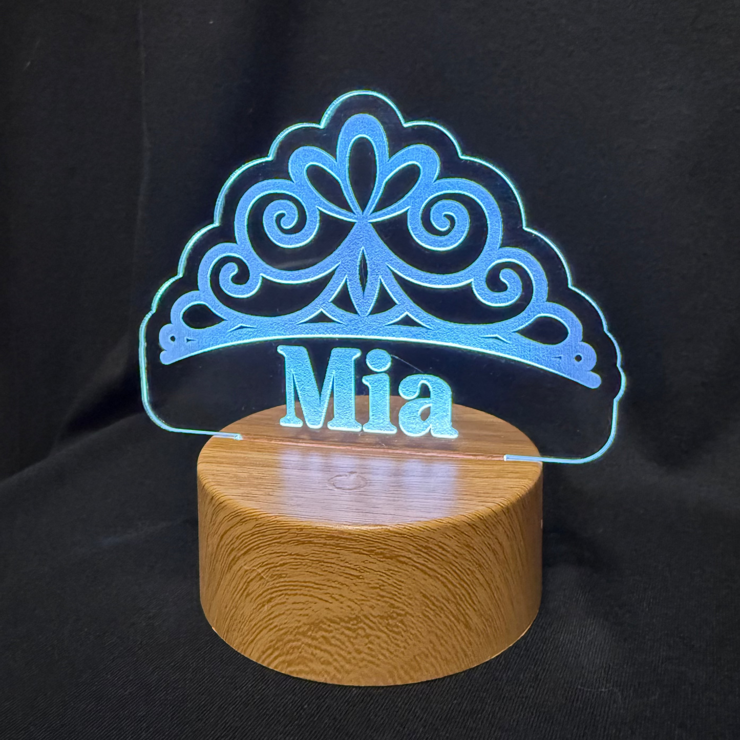 Decorative lamp with a tiara design and 'Mia' text on a black background