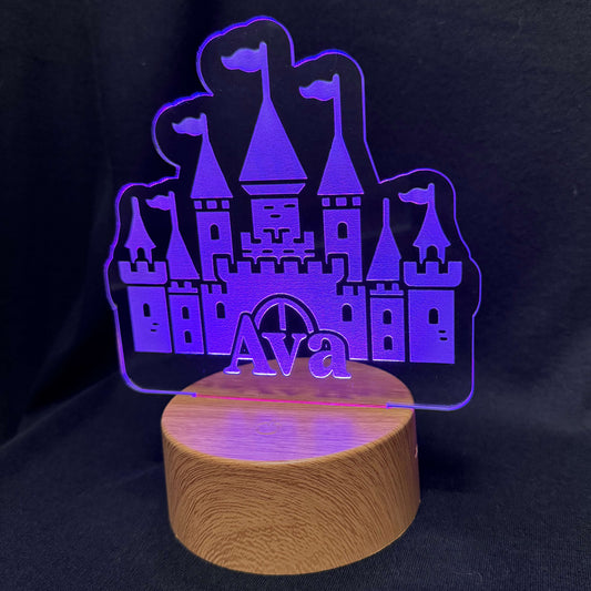 Purple castle-shaped LED lamp with 'Ava' on a wooden base against a black background