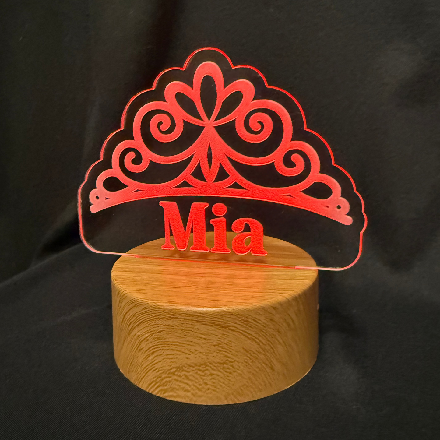 Decorative lamp with 'Mia' on a wooden base against a black background