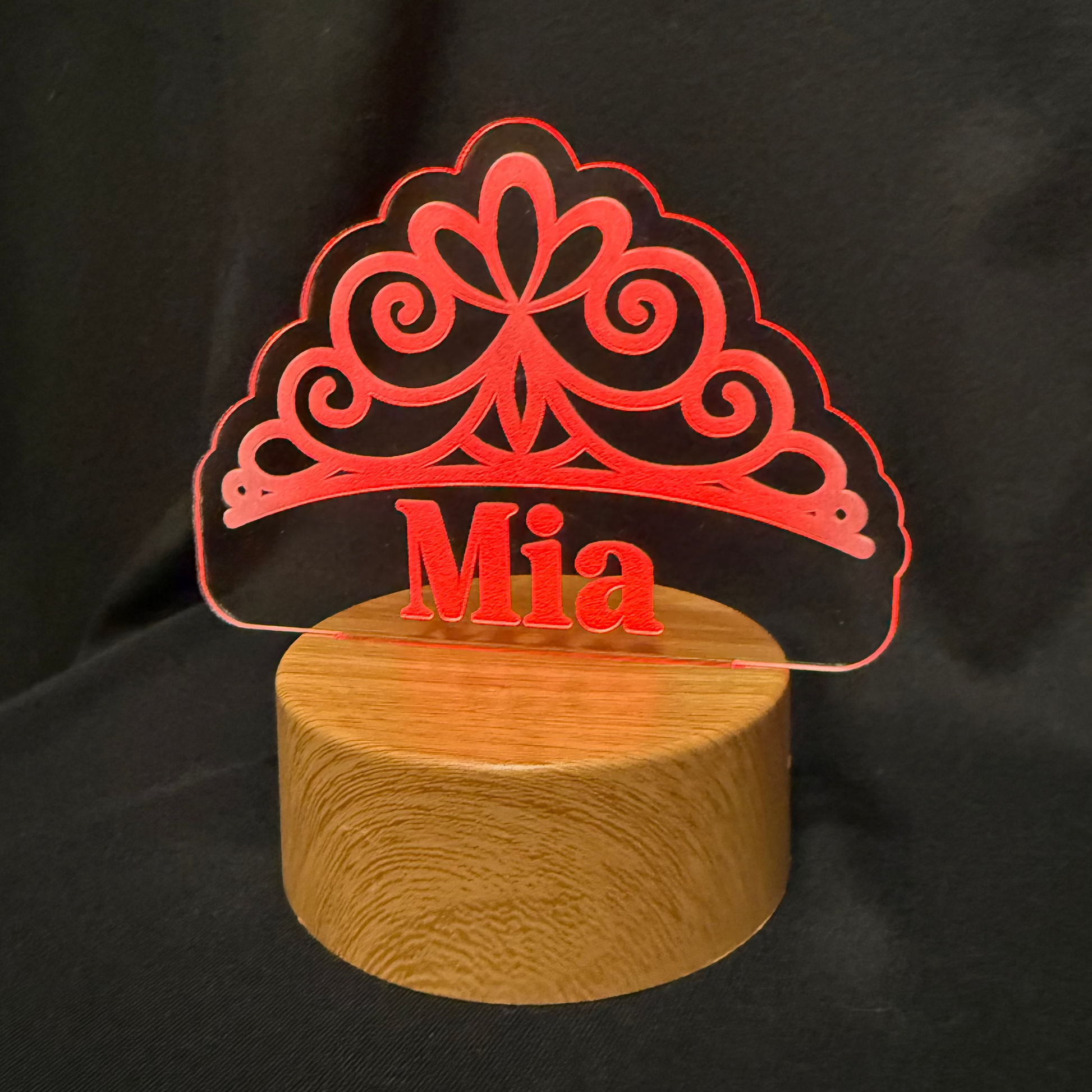 Decorative lamp with 'Mia' on a wooden base against a black background