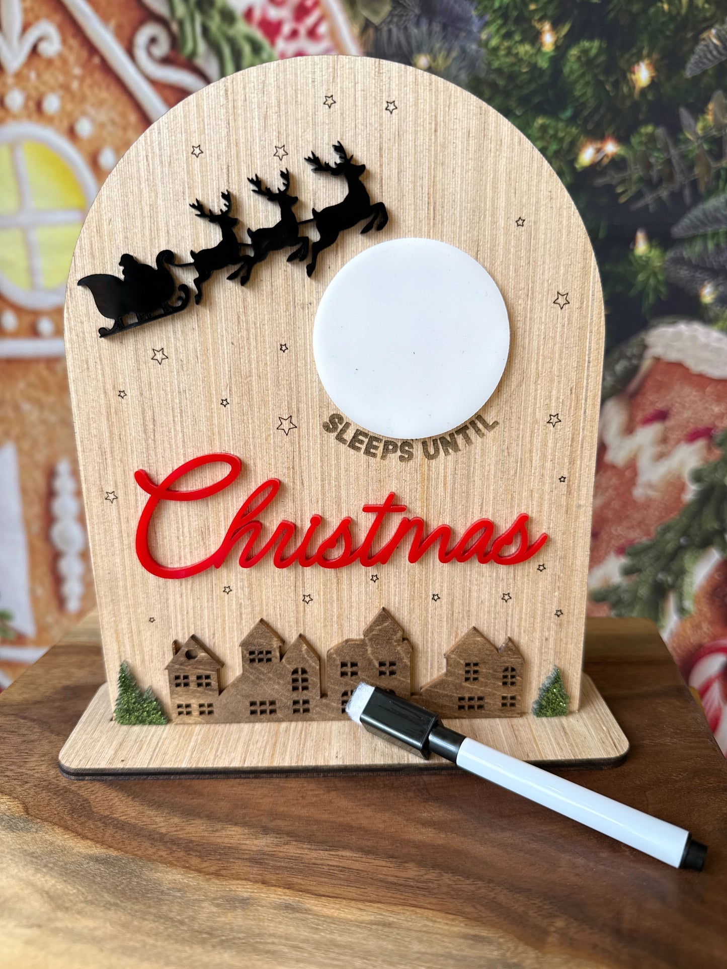 Small wooden sign with a dry erase moon that says (blank) sleeps until Christmas with Santa's sleigh and a holiday village 