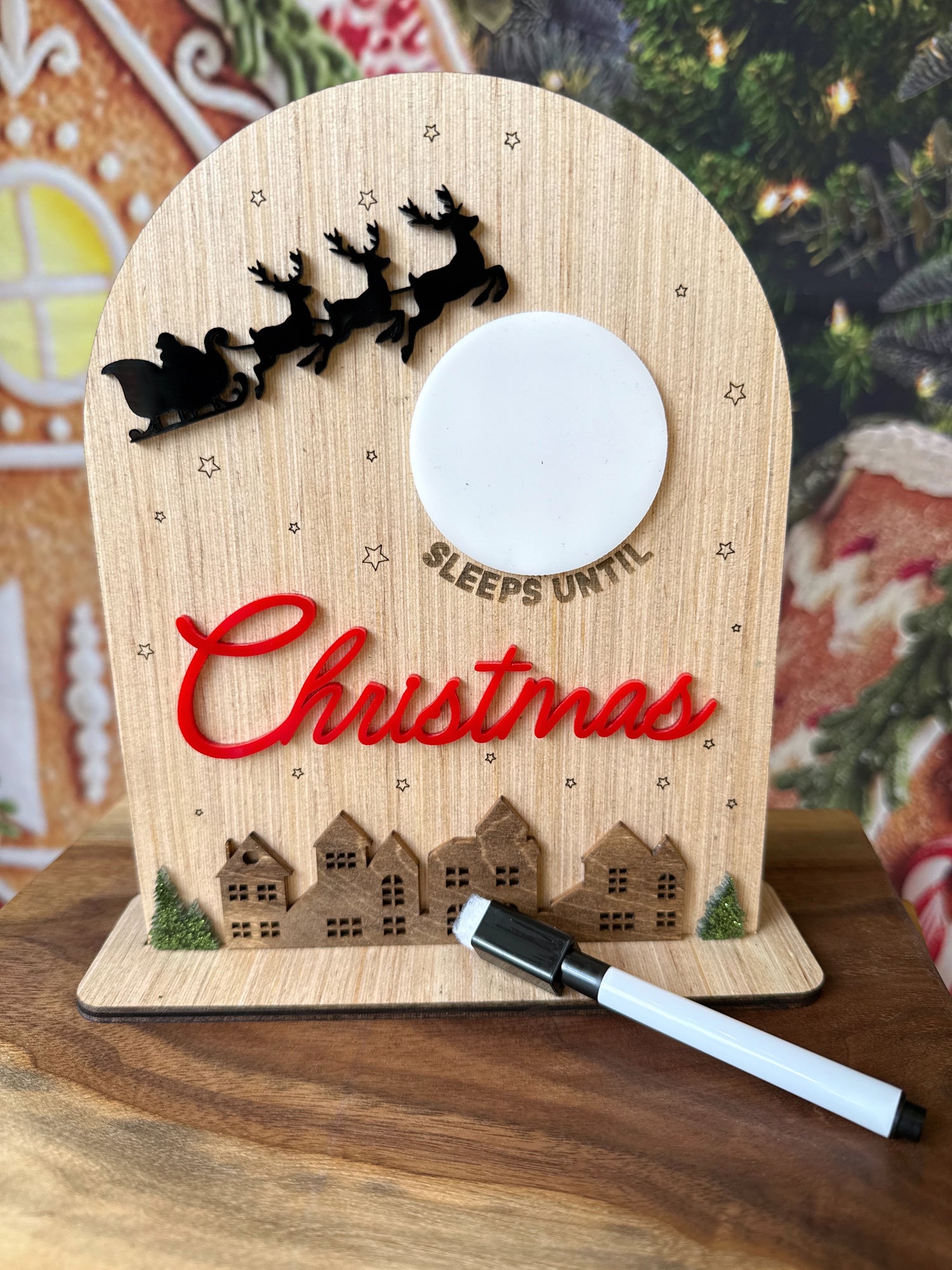 Small wooden sign with a dry erase moon that says (blank) sleeps until Christmas with Santa's sleigh and a holiday village 