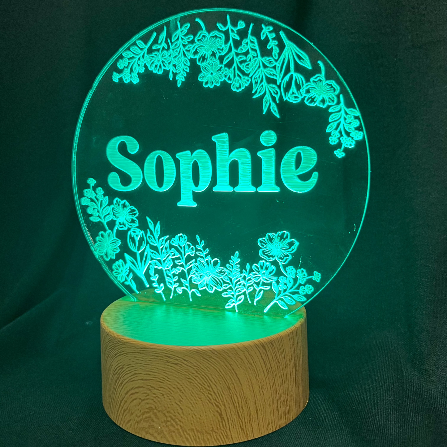 Personalized Wildflower Name Night Light featuring laser-engraved wildflowers surrounding a custom name on a clear acrylic panel, softly illuminated by an LED light on a wooden base