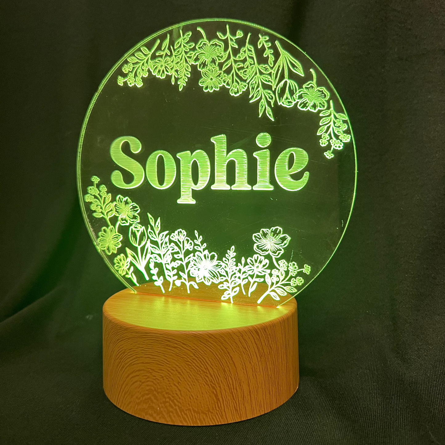 Personalized Wildflower Name Night Light featuring laser-engraved wildflowers surrounding a custom name on a clear acrylic panel, softly illuminated by an LED light on a wooden base