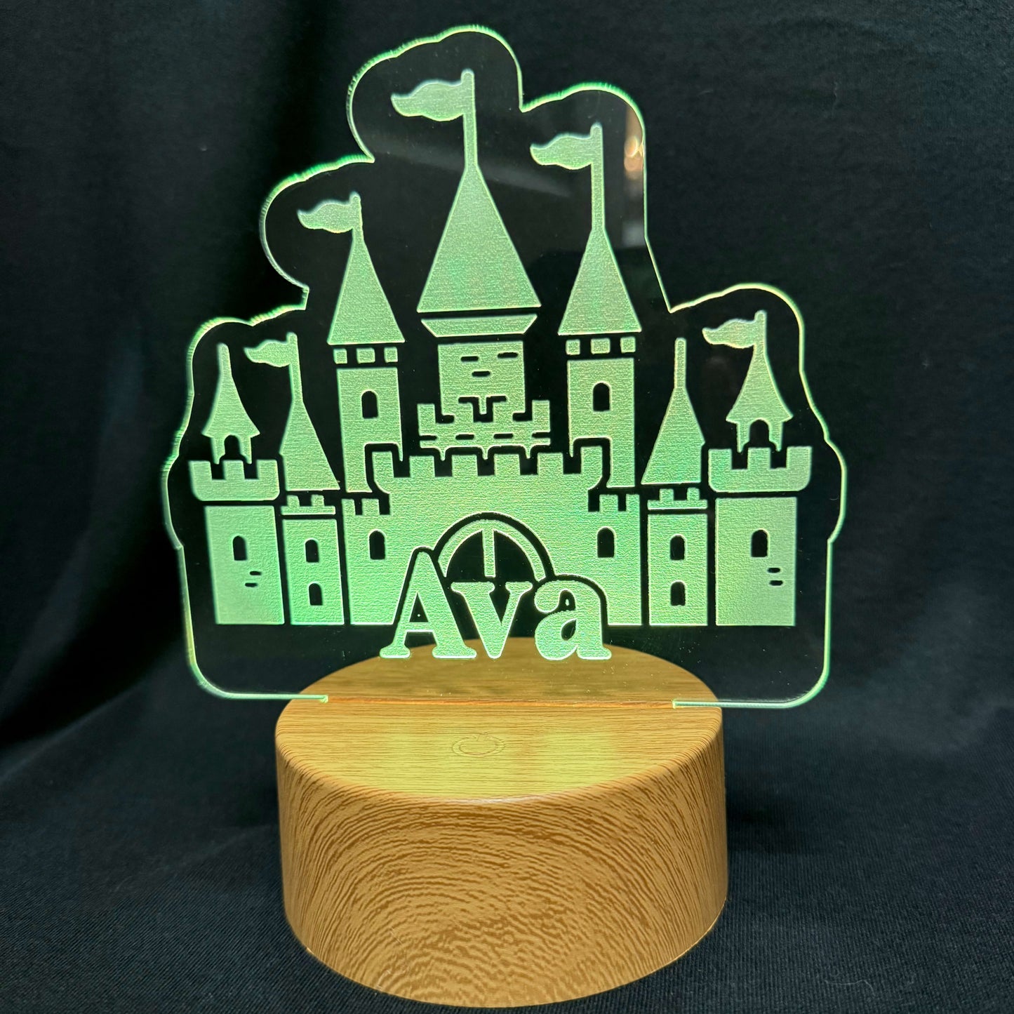 Glowing castle-shaped night light with 'Ava' on a wooden base against a dark background